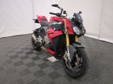 une photo d'une moto rouge et noire garée sur un sol à damier noir et blanc