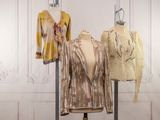 two women ' s jackets on a mannequin stand in front of a white wall