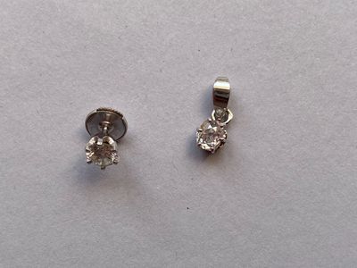 une paire de boucles d'oreilles en diamant posées sur une surface blanche
