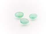 a group of three green glass tear shaped beads on a white surface