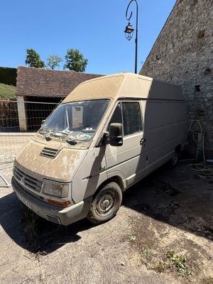 Une vieille camionnette est garée devant un immeuble en briques.