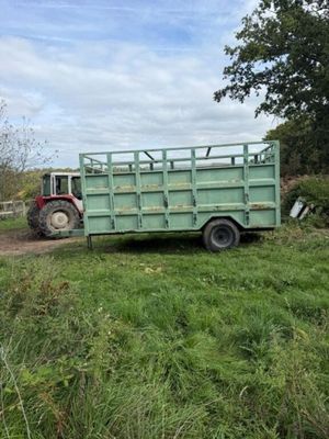 a tractor that is parked next to a green trailer
