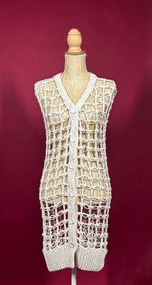 white crocheted vest on a mannequin stand against a red background