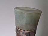 a green vase sitting on top of a wooden stand