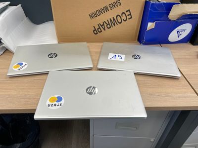 trois ordinateurs portables posés sur un bureau, à côté d'un carton