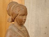 a wooden statue of a woman sitting on a table