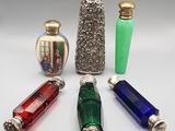 four different colored glass vases and a silver vase on a white surface