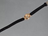 a close up of a watch on a black strap with a gold clasp