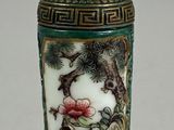 un vase vert avec un couvercle doré posé sur une table