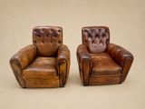 deux fauteuils en cuir marron placés l'un à côté de l'autre sur une surface beige