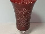 un vase en verre rouge posé sur une table blanche