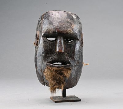un gros plan d'un masque en bois barbu posé sur un socle