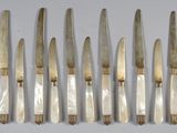 six knives are lined up in a row on a white surface