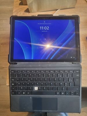 Quelqu'un tient un ordinateur portable dont l'écran est bleu, posé sur une table.