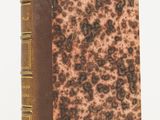 a brown book sitting on top of a table next to a white wall