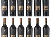 six bottles of red wine are lined up on a white surface