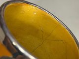 a close up of a yellow vase on a table