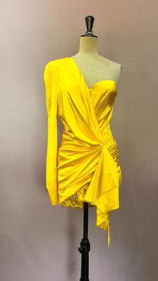a yellow dress on a mannequin stand against a wall