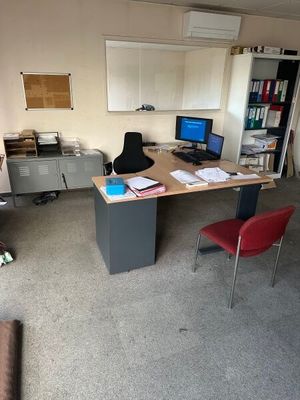 a desk with a computer and a chair in a room