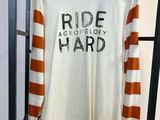 Une chemise blanche à rayures orange et blanches est suspendue à un portant.