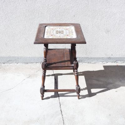 une petite table en bois recouverte d'un plateau en faïence