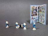 toy figurines of the smurfs are standing in front of a book
