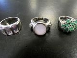three different rings with green and white stones on a black surface
