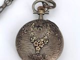 a silver pocket watch on a chain with a bird on it