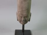 sculpture représentant une tête posée sur un socle, avec un fond blanc