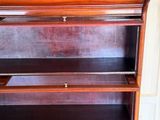 a wooden bookcase with a glass door and a painting on the wall