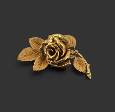 un gros plan d'une rose dorée avec des feuilles sur fond noir