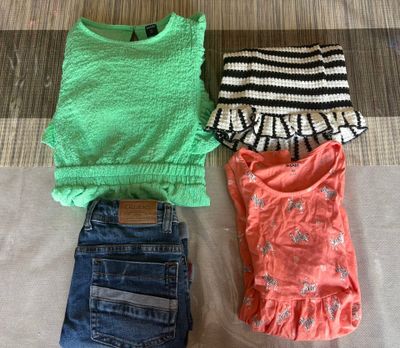 three pairs of clothes are laid out on a bed