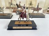 many miniature figurines of men riding horses in glass cases