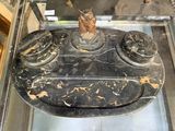 une vitrine en verre posée sur une table en marbre noir sur laquelle se trouve une statue