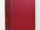 an old red book sitting on top of a white table
