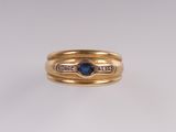 gros plan d'une bague en or avec un saphir et des diamants