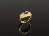 une bague en or sertie d'un saphir et de diamants sur un fond noir