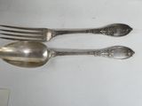 two silver spoons and a fork on a table