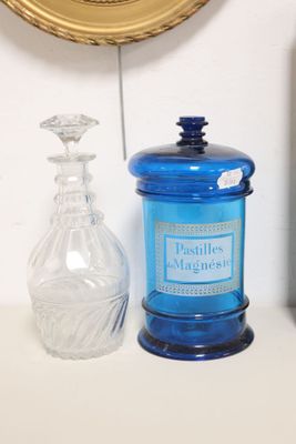 a blue glass jar sitting on a shelf next to a clock