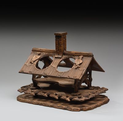 une image représentant une maquette en bois d'une maison posée sur un rocher
