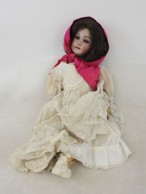 une poupée assise par terre, vêtue d'une robe