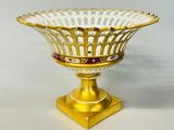 une image représentant un bol en verre doré et blanc posé sur un socle doré