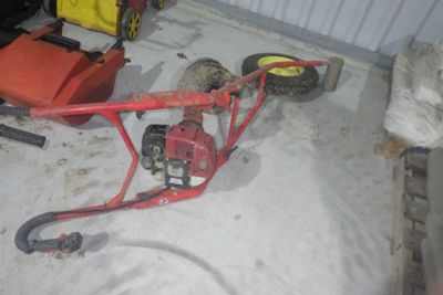 une petite tondeuse à gazon rouge rangée dans un garage