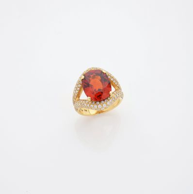 une bague en diamant et pierre rouge posée sur un fond blanc