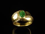 a close up of a gold ring with a green stone
