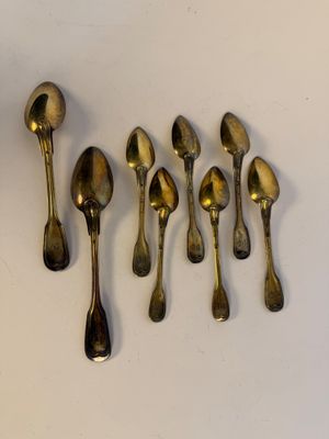 six spoons and a spoon rest on a white surface