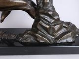 bronze statue of a woman sitting on a rock with her hands on her face