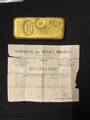 an old gold bar sitting on top of a piece of paper next to a piece of paper