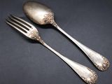 two silver spoons and a fork on a black surface