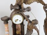a statue of a man holding a clock next to a statue of an eagle